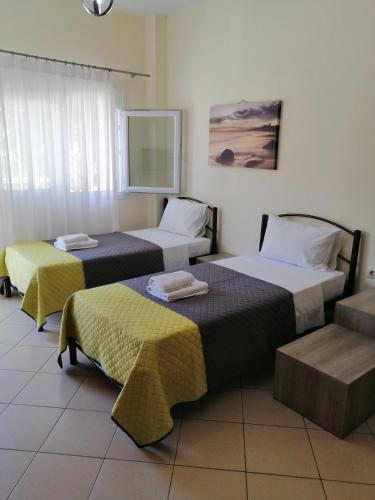a hotel room with two beds and a window at Sunny summer time in Nea Vrasna