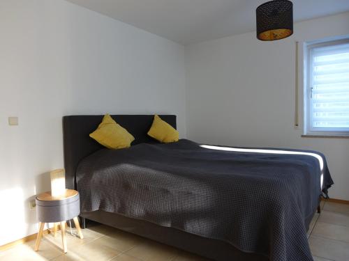 1 dormitorio con cama negra y almohadas amarillas en Exclusive cozy apartment in the heart of Franconia, en Gaukönigshofen
