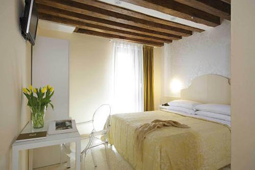 ヴェネツィアにあるホテル アドリアティコのベッドルーム1室(ベッド1台、テーブル、窓付)