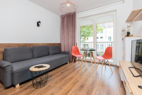 een woonkamer met een bank en een tafel en stoelen bij Rewita Wrzeszcz Apartments by Renters in Gdańsk