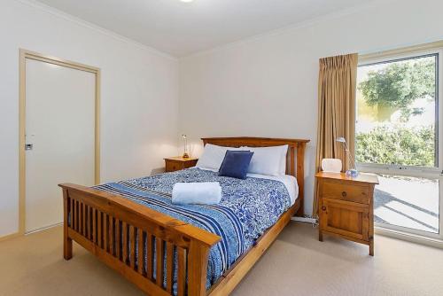 a bedroom with a wooden bed and a window at Family Tides Holiday Home in Apollo Bay