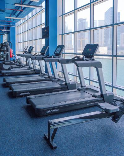 a row of treadmills in a gym with windows at Canal Central Hotel Business Bay in Dubai