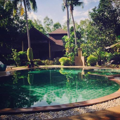 a swimming pool in front of a house with palm trees at Phalarn Inn Resort in Mae Nam