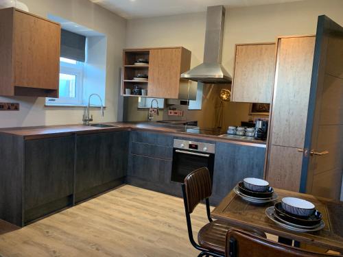 uma cozinha com armários de madeira e uma mesa com pratos em Oddfellows Hall em Thetford