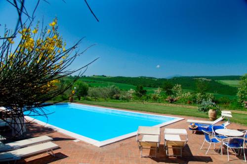 a swimming pool with chairs and a table at Agriturismo Il Casalone in Montepulciano