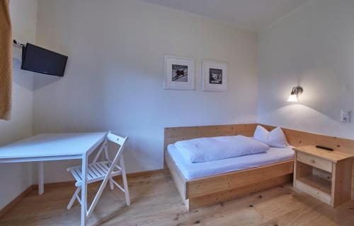 a small bedroom with a bed and a desk at Sportpension Enzian in Saalbach Hinterglemm