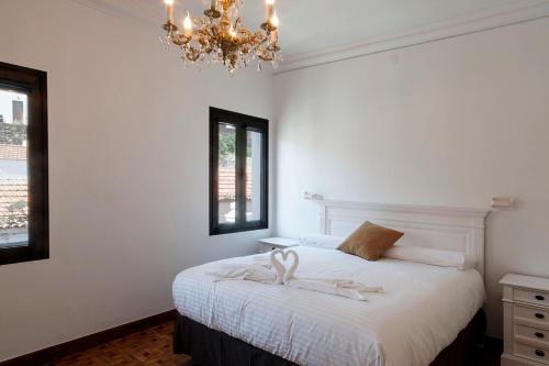 een slaapkamer met een wit bed en een kroonluchter bij ELHIERRO BED&URBAN I in Valverde