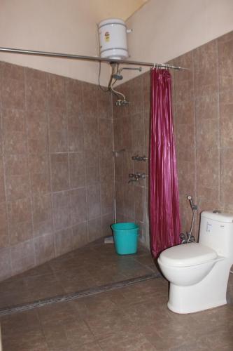 バラナシにあるCozy Innのバスルーム(トイレ、赤いシャワーカーテン付)