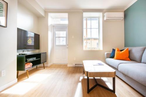 a living room with a couch and a tv at Appart Hôtel Le Saint-Anselme - Par Revenus Locatifs Qc in Quebec City