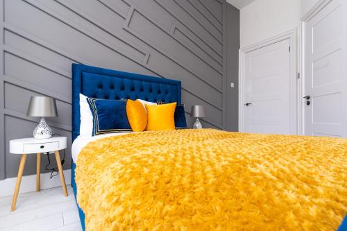 a bedroom with a large bed with a yellow blanket at Cheerful 2 Bedroom Homely Apartment, Sleeps 4 Guest Comfy, 3x Double Bed, Parking, Free WiFi, Suitable For Business, Leisure Guest,Glasgow, Glasgow West End, Near City Centre, Perfect For Common Wealth Games 2026 in Glasgow