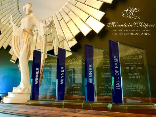 a row of awards on a table with a statue at Mountain Whispers Varenna Luxury in Leura