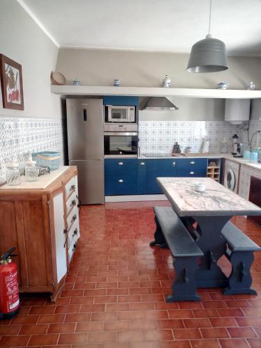 a kitchen with blue cabinets and a table in it at Alojamento local Angel`s in Ponte da Barca