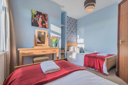 a bedroom with two beds and a desk with a tv at Big White House in Cockermouth