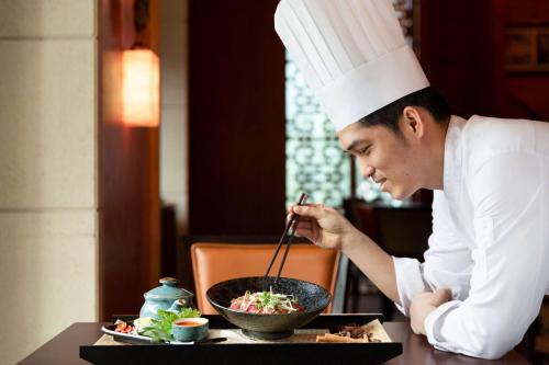 a man in a chefs hat stirring a bowl of food at Shangri-La Dubai in Dubai