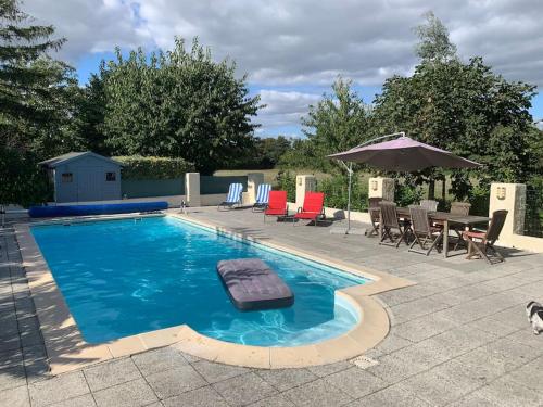 a swimming pool with chairs and a table and an umbrella at Les Roches in Vanzay