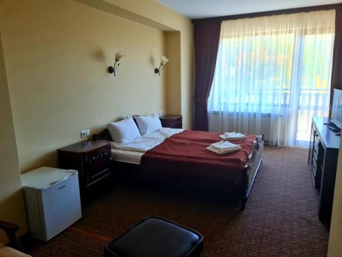 a hotel room with a bed and a television at Family Hotel Bela in Tryavna