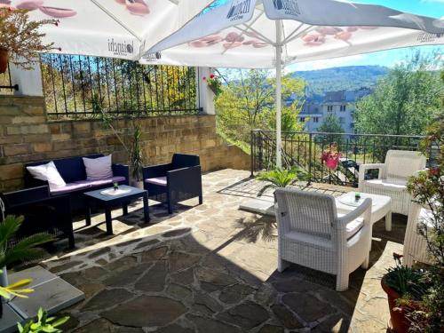 a patio with tables and chairs and an umbrella at Family Hotel Bela in Tryavna