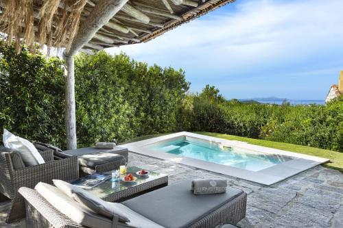 a patio with a pool and a table and chairs at Hotel Li Finistreddi in Cannigione