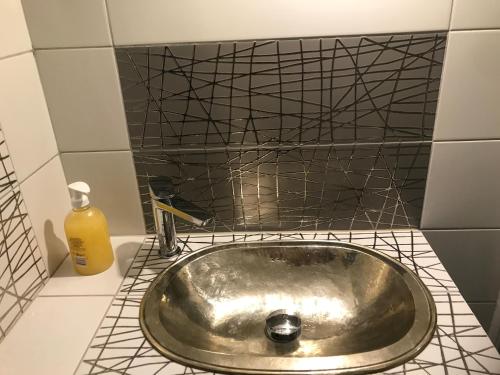 ein silbernes Waschbecken im Bad mit schwarzen Fliesen in der Unterkunft 7 Métris in Corre