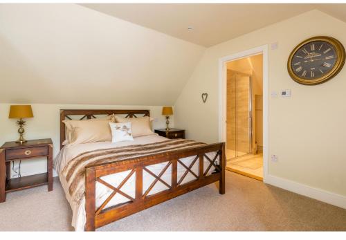 1 dormitorio con 1 cama y reloj en la pared en The Cartlodge, en Wickham Bishops