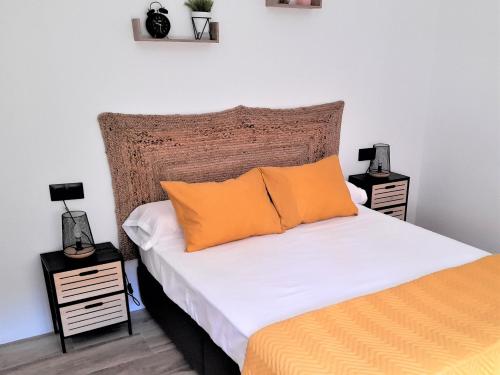 um quarto com uma cama com almofadas laranja e duas mesas de cabeceira em La CaSita em Vara de Rey