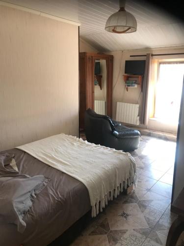 ein Schlafzimmer mit einem Bett und einem Ledersessel in der Unterkunft 7 Métris in Corre