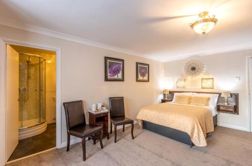 a bedroom with a bed and two chairs at Fox & Hound Hotel in Guisborough