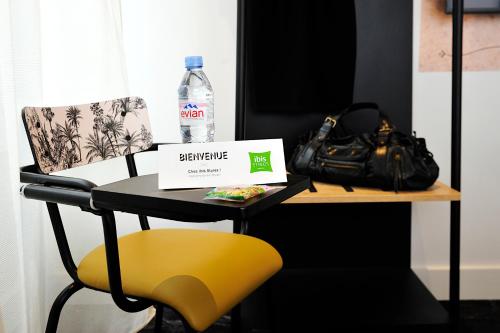 a table with a bottle of water and a yellow chair at ibis Styles Paris Gare De Lyon TGV in Paris