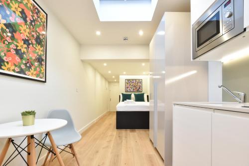 uma cozinha e sala de estar com uma mesa e uma cama em Earls Court East Serviced Apartments by StayPrime em Londres