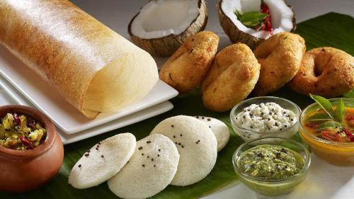 uma mesa com vários tipos de pão e molhos em Temple Plaza Kochi em Chottanikara