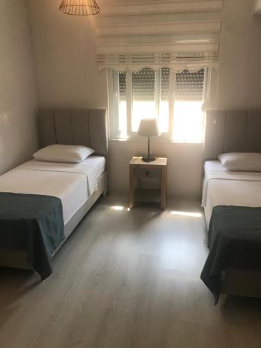 a bedroom with two beds and a table with a lamp at Nefes evleri in Demre