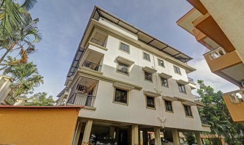 a white building with windows and a palm tree at Treebo Aquamarine Arpora With Pool in Arpora