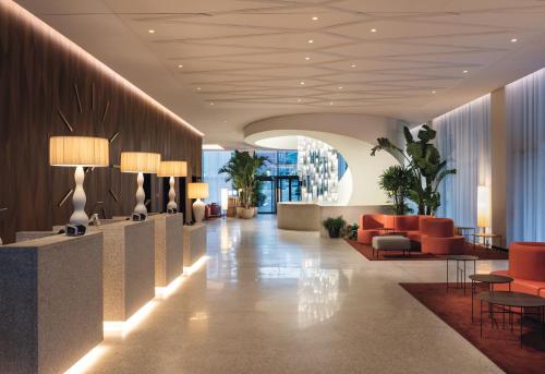 a lobby of a hotel with orange chairs and tables at Mövenpick Hotel Basel in Basel
