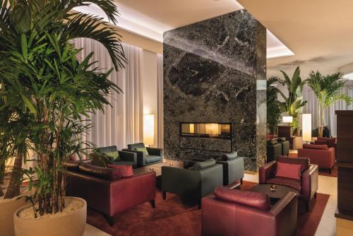 a lobby with couches and plants and a fireplace at Mövenpick Hotel Basel in Basel