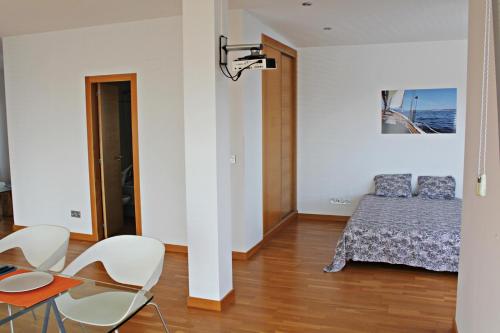 een slaapkamer met een bed en een tafel en stoelen bij Precioso apartamento, espectaculares vistas. in Cangas de Morrazo