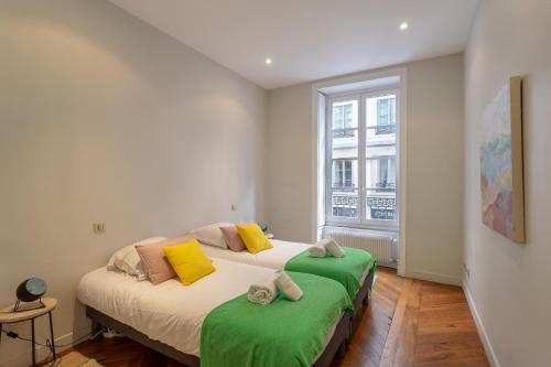a bedroom with two beds with green and yellow pillows at DIFY Le Franklin - Bellecour in Lyon