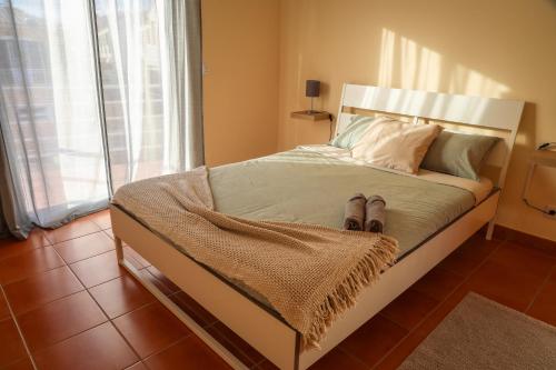 a bedroom with a bed with a pair of shoes on it at O DRAGOEIRO da Madalena! in Porto Santo