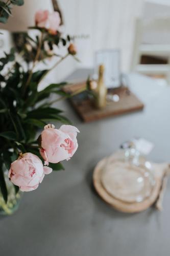 a table with a vase of pink flowers and a plate at De vijgenhof in Appingedam