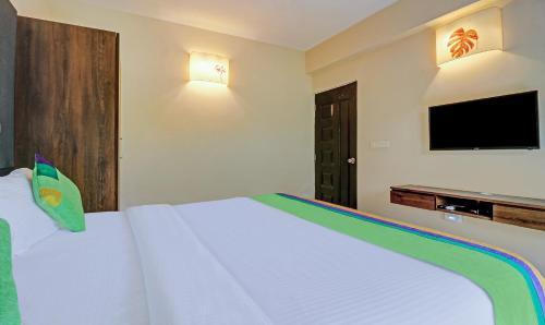 a bedroom with a white bed and a flat screen tv at Treebo Aquamarine Arpora With Pool in Arpora