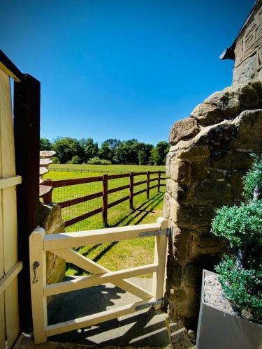 a wooden gate with a fence and a field at Kingfisher Lodge in Froggatt