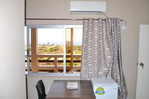 a room with a table and a window with a table and chair at Ponta View Hotel in Ponta do Ouro