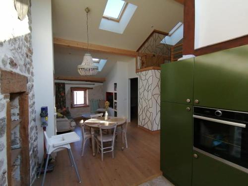 a kitchen with a table and a green refrigerator at Joubarbe Les Herbes de la Saint Jean in Saint-Bonnet-le-Froid