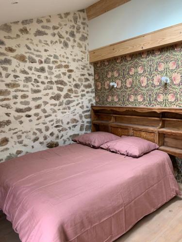 Cama en habitación con pared de piedra en Joubarbe Les Herbes de la Saint Jean, en Saint-Bonnet-le-Froid