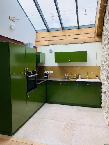 a kitchen with green cabinets and a glass ceiling at Joubarbe Les Herbes de la Saint Jean in Saint-Bonnet-le-Froid