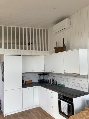 a kitchen with white cabinets and a black counter top at Cabin in the woods, close to Lake Mälaren in Eskilstuna