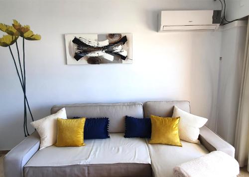 マルベーリャにあるBeachfront Studio Apartment Marbellaのリビングルーム(カウチ、黄色と青の枕付)