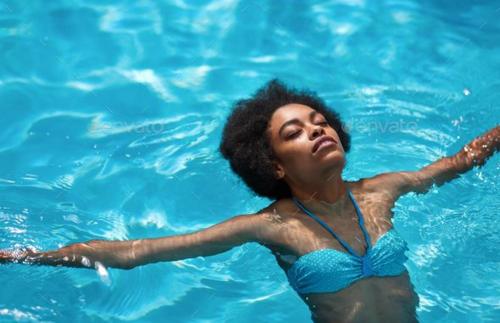 a woman swimming in a pool of blue water at The Seyyida Hotel and Spa in Zanzibar City