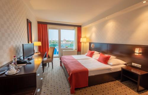 a hotel room with a bed and a desk and a television at Hunguest Hotel Gyula in Gyula
