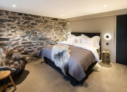 ein Schlafzimmer mit einer Steinmauer und einem Bett in der Unterkunft Godo Lodge in Godøy