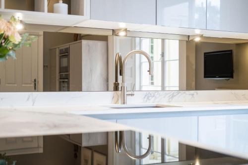 uma cozinha com balcões brancos e um lavatório em Wellington Square - By Luxury Apartments em Cheltenham